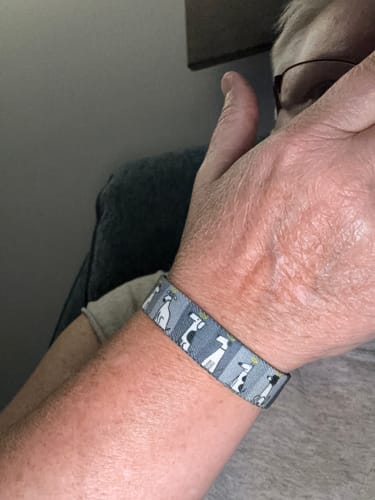 Customer's gray All Dogs Go To Heaven bracelet with dog patterns worn on their wrist.