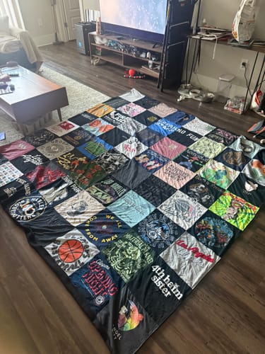 Customer's Project Repat T-Shirt Quilt spread out on a wooden floor, featuring various colorful fabric squares.