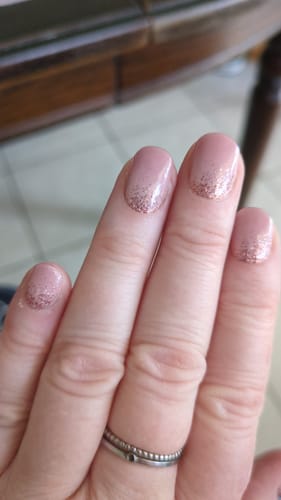 Reviewer's hand showing UV Nagelfolien with a delicate pink and glitter ombre design.