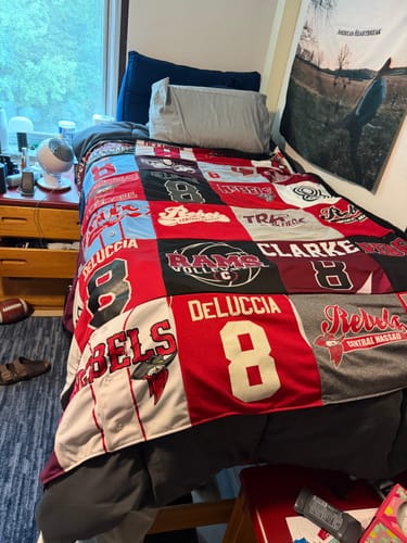 Customer's Project Repat T-Shirt Quilt made of colorful sports jerseys draped over a dorm bed.