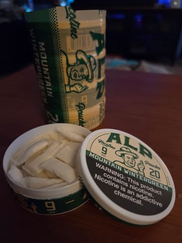 Customer's open tin of Mountain Wintergreen nicotine pouches next to a stacked five-pack of pouches.