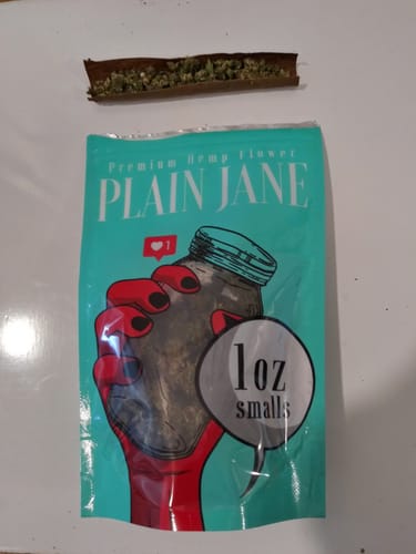 Customer's 1 Oz Small Buds in a bright teal bag next to a brown wrap containing the flower.