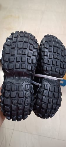Customer's pair of Colossus sneakers held up, showing the thick, trail-style black rubber outsoles.