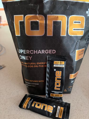 Customer's Rone SuperCharged Honey classic 20-pack bag standing upright with two individual honey sticks in front.