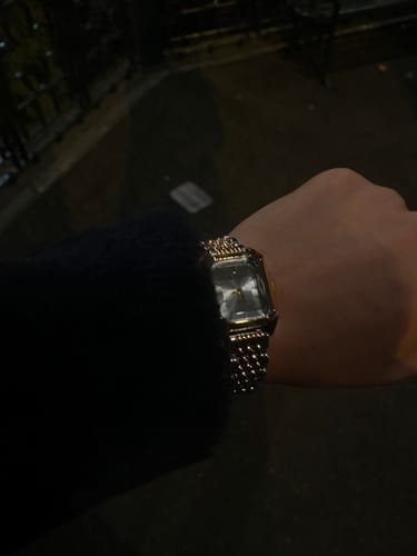 Reviewer's Claire De Mains watch in gold-tone, showing a close-up of the textured bracelet on a wrist.