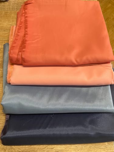 Customer's fabric bundle from the £0.25 Per Metre Fabric Bundle, showing four stacked layers of colorful plain fabric.