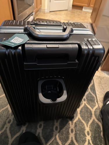 Reviewer's black Lifetime Warranty carry-on suitcase, showing the integrated cup holder and handle, indoors.