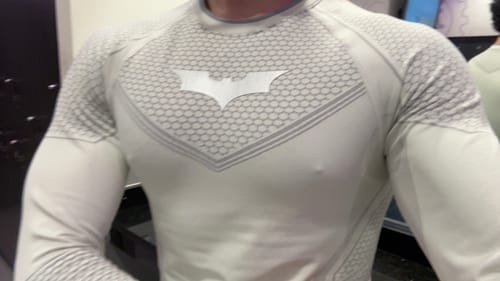 Customer's white Batman Compression Tee on torso, showing the textured fabric and emblem in a gym setting.