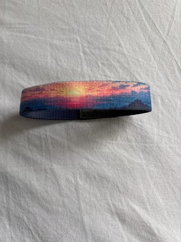 Customer's One Day At A Time bracelet with a colorful sunset landscape design on a white surface.