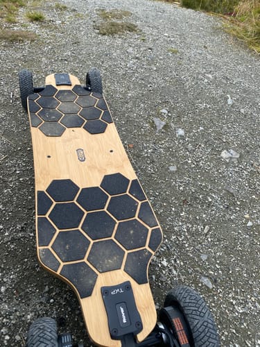 Customer's MEEPO ROVER electric skateboard with honeycomb grip tape, on a gravel path.
