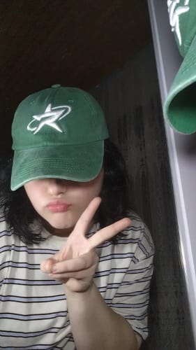 Customer's Radikal Merch acid wash yeşil şapka on their head while giving a peace sign.