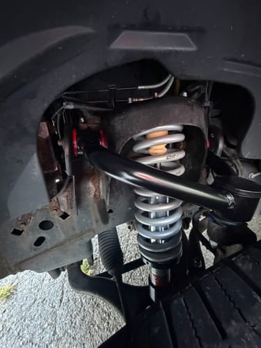 Reviewer's installed black Ford F150 upper control arm attached to the suspension system, close-up view.