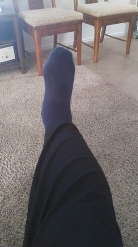 Customer's Eucalyptus Lyocell Compression Socks on a leg, showing the dark blue color while resting on a carpet.