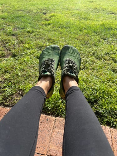 Reviewer's green Free I barefoot shoes worn outdoors on grass.