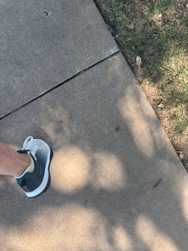 Customer's CUURT Muuv court shoe being worn on a concrete sidewalk.