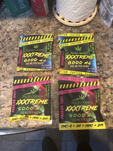 Reviewer's four XXXtreme Gummies packages arranged on a kitchen counter surface.