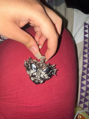 Customer's silver Till Death Do Us Part pendant being held by a hand, showing the skull heart shape.