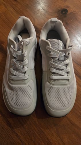 Customer's pair of light gray CUURT Muuv court shoes with wide toe boxes resting on a wooden floor.