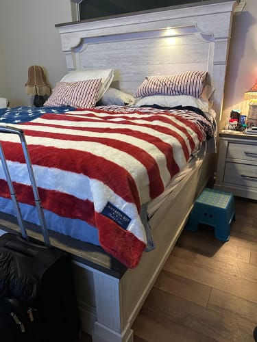 Customer's Lush Flag Blanket on a king-sized bed with striped bedding underneath, visible Minky Couture label.