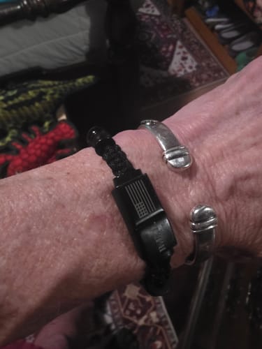 Customer's R.E.D. Tiger's Eye Never Forget Bracelet worn on wrist alongside a silver cuff bracelet.