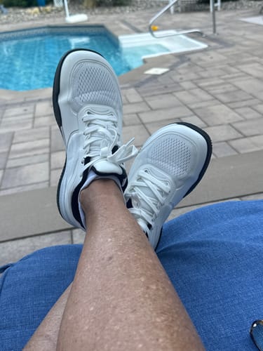 Customer's white CUURT Muuv court shoes with wide toe boxes resting by a backyard pool.