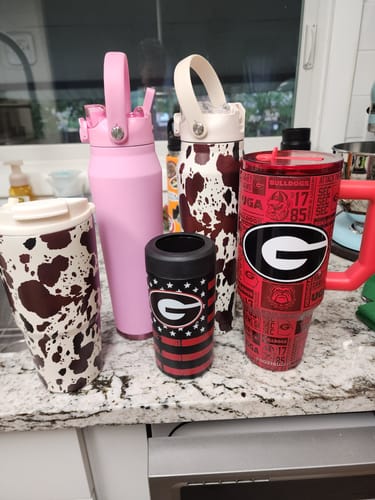 Customer's collection of five Frost Buddy containers with cow print, solid pink, and Georgia Bulldogs team patterns.