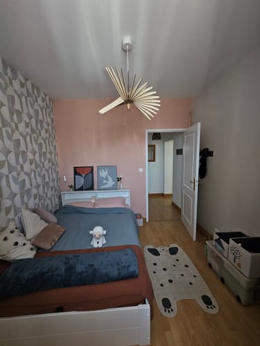 Customer's Mini Néo Applique luminaire en bois installée au plafond dans une chambre aux tons roses et bleus.