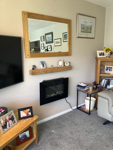 Customer's rustic oak fireplace beam installed as a floating mantel shelf above a wall-mounted electric fireplace.