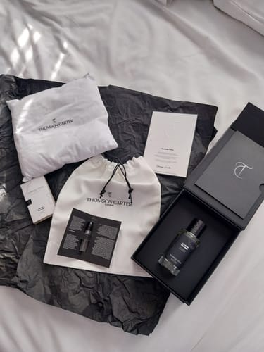 Customer's Lilium Blume perfume bottle, cloth bag, and inserts arranged neatly on wrinkled dark paper.