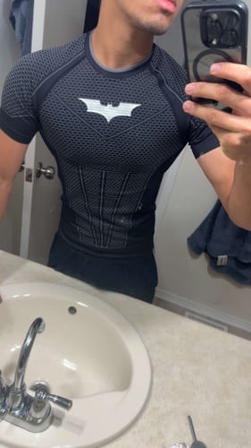 Reviewer wearing a black Batman Compression Tee featuring a structured armor pattern and white chest emblem.