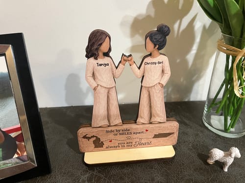 Customer's personalized wooden plaque showing two figures doing a pinky promise, standing on a wooden display base.