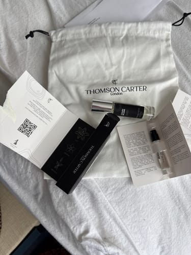 Customer's Lilium Blume Eau de Parfum with travel spray, sample vial, and branding packaging on a white fabric surface.