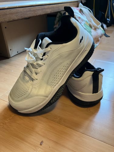 Customer's pair of white CUURT Muuv court shoes with a black interior on a wooden floor.