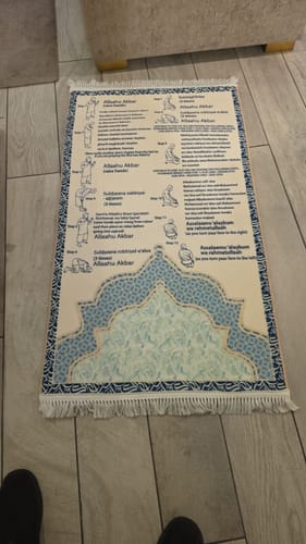 Customer's Step-by-Step Phonetic Salah Padded Prayer Mat laid flat on a light wood floor with instructional diagrams.