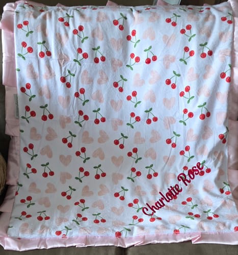 Customer's Custom Blanket Personalization with a cherry print pattern and the name Charlotte Rose embroidered on it.
