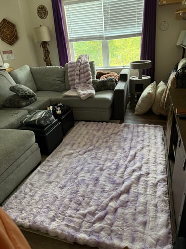 Customer's Extreme Ultra Cloud Lilac Breeze Blanket laid out as a rug in front of a gray couch in a living room.