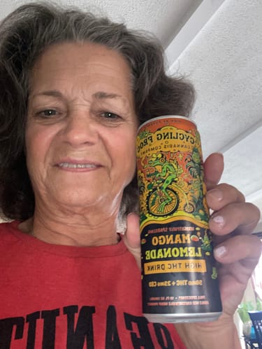 Reviewer holding a can of Cycling Frog Mango Lemonade THC drink
