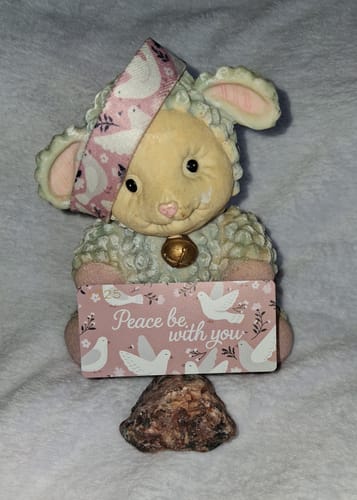 Customer's Peace Be With You bracelet placed on a small lamb figurine standing on a rock.
