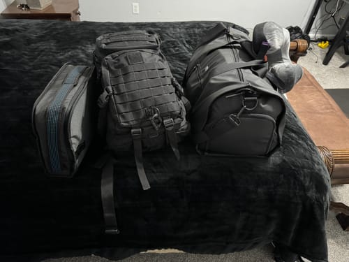 Customer's Aerless Weekender bag along with a backpack and a small travel case sitting on a bed.