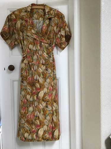 Customer's floral Tulip Impression viscose dress hanging on a door, showing the wrap front and elegant drape.