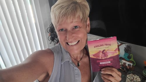 Customer smiling and holding a packet of Passionfruit Gummies while indoors