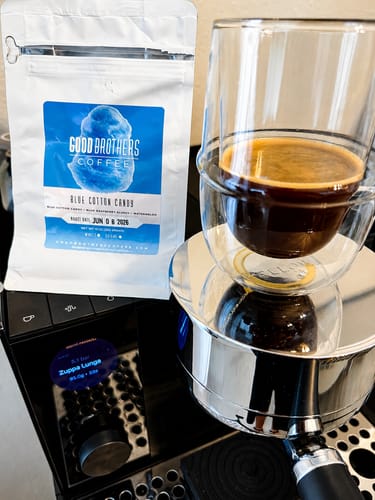 Customer's Blue Cotton Candy coffee bag and a freshly brewed cup of espresso on a modern coffee machine.