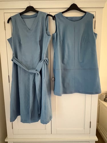 Customer's two light blue dresses made from Plain Stretch Denim Fabric, hanging on hangers.