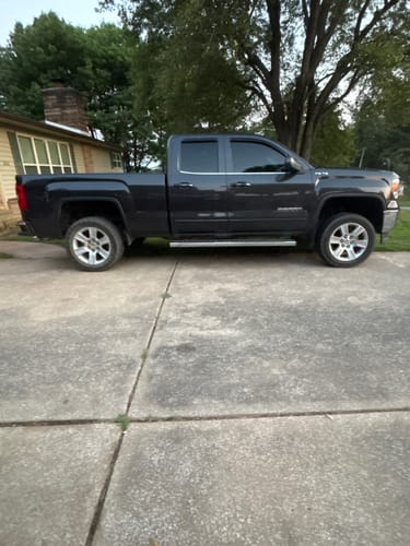 Customer's black lifted truck parked on a concrete driveway after installing the suspension lift kit.