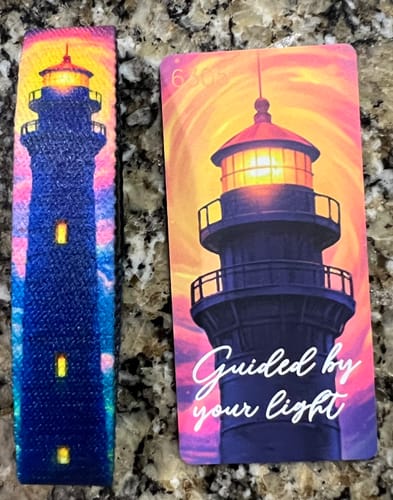 Customer's Guided By Your Light Bracelet next to its matching collector card with a lighthouse design.