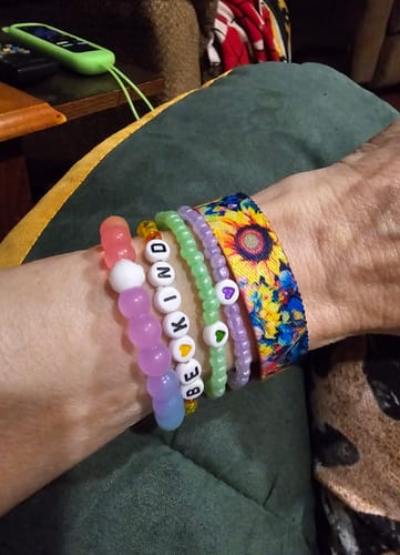 Reviewer's arm wearing a colorful Radiate Positivity Bracelet and stack of beaded bracelets.