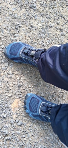 Customer's blue Active II Pro barefoot shoes worn while standing on a stoney ground surface.