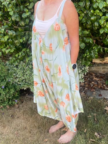 Customer's Spring Petals Viscose Challis Fabric worn as a loose, floaty dress against a leafy green background.