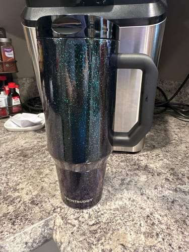 Customer's teal and black glittery Thicc Buddy mug with a sturdy black handle standing on a kitchen counter.