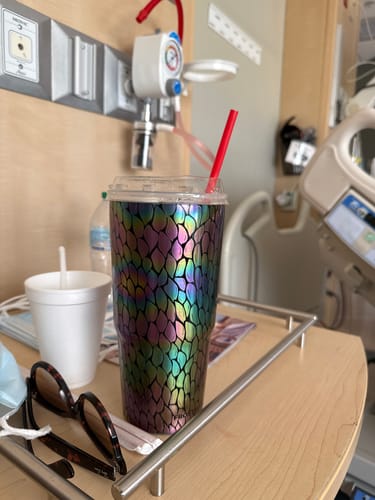 Customer's To-Go Buddy in metallic iridescent color, sitting on a bedside tray in a hospital room.